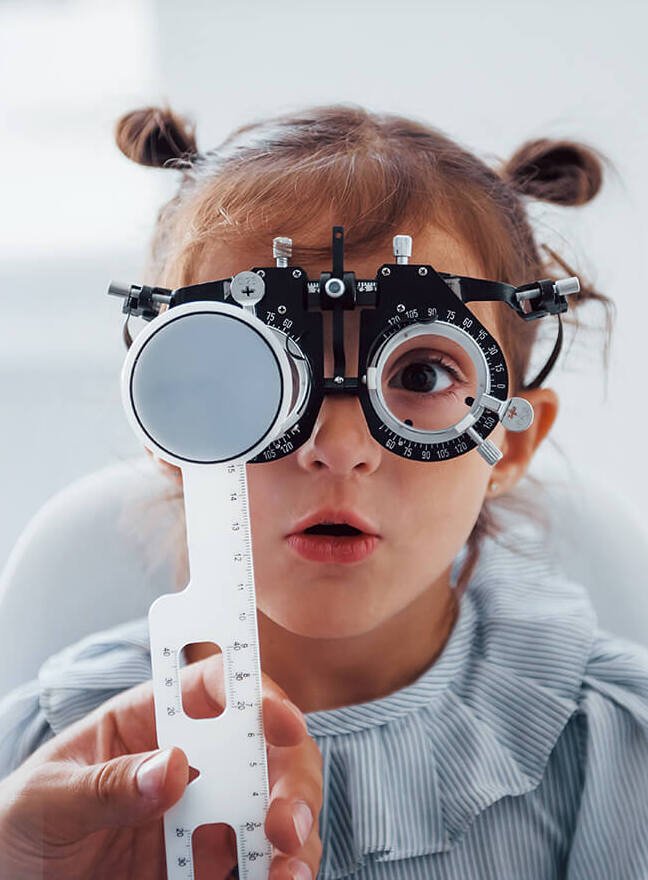 Copil la o consultație optometrică, cu ochelari de probă
